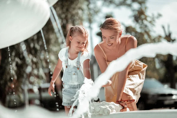 분수 근처에서 딸과 놀고있는 아름다운 여자. — 스톡 사진