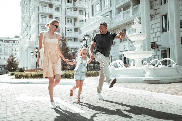 Little girl and her parents skipping along the street. — Stock Photo, Image