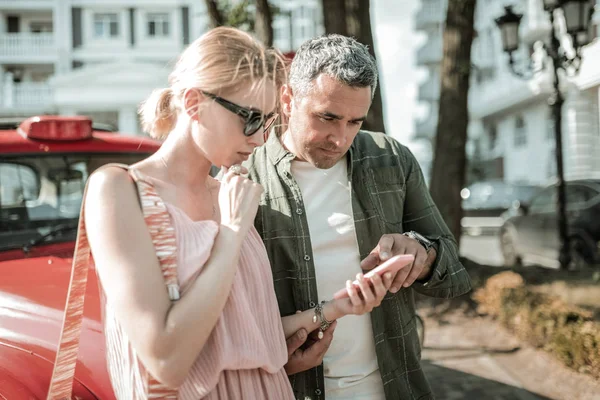 Man helping his wife with her smartphone.