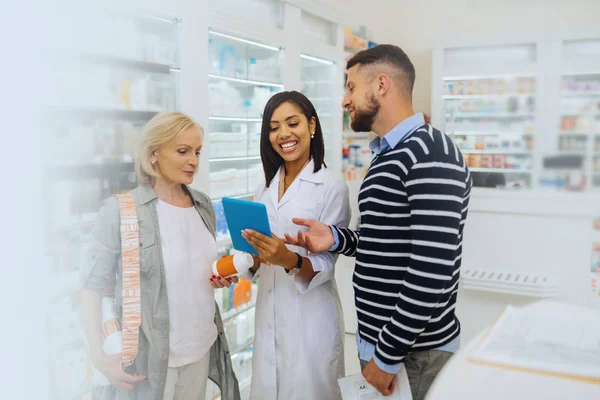 Erstaunliche dunkelhäutige Apothekerin, die ihr Gerät betrachtet — Stockfoto