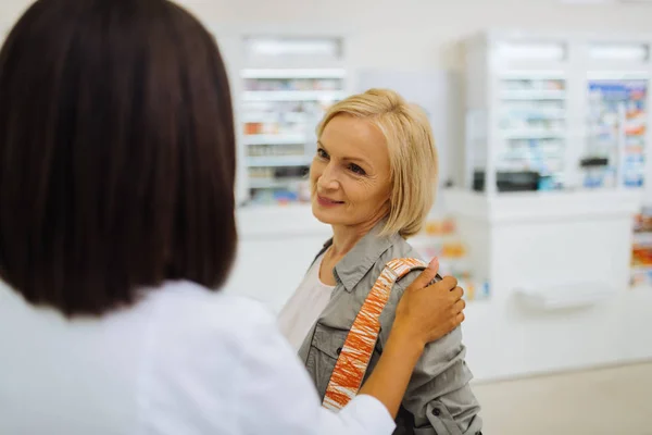 Snäll mogen kvinnlig person tittar på apotekare — Stockfoto