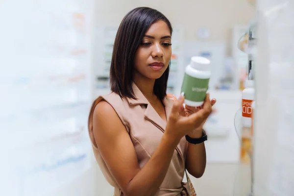Mujer de piel oscura concentrada mirando nuevas vitaminas — Foto de Stock