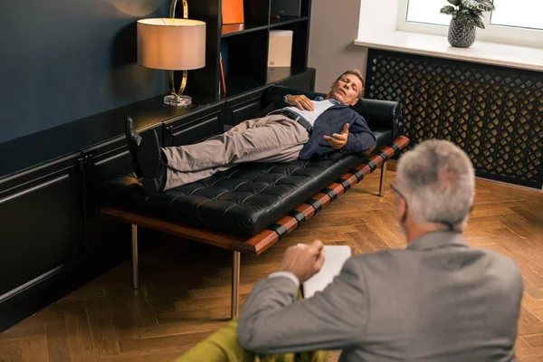 Hombre en el sofá hablando con un psicoterapeuta — Foto de Stock