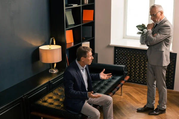 Serious Caucasian psychiatrist listening to his worried patient — Stock Photo, Image