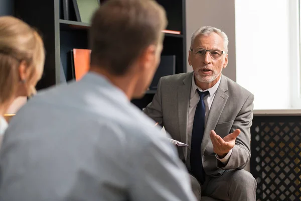 Psicoterapeuta profesional de pelo gris seguro y guapo consultando a pareja casada — Foto de Stock