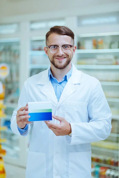 Guapo joven químico demostrando paquete con la medicina — Foto de Stock