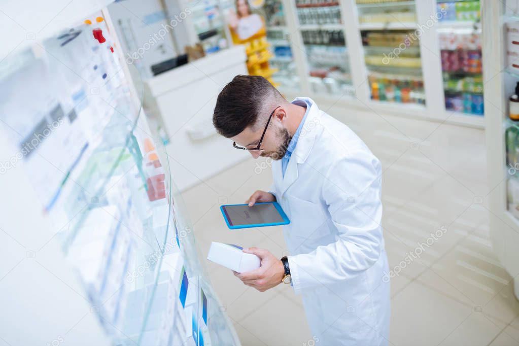 Young apothecary staring at package with medicine