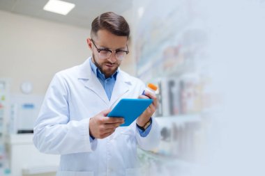 Tablet ekranına bakan özenli esmer eczacı