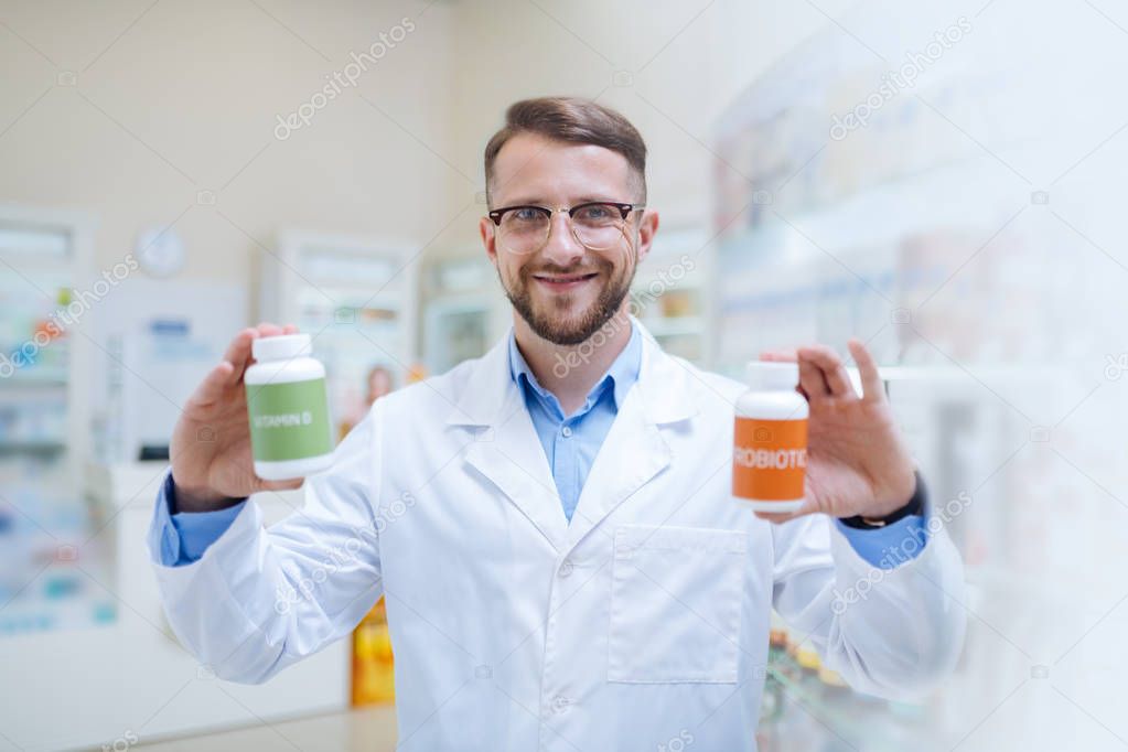 Cheerful young bearded apothecary giving useful recommendations