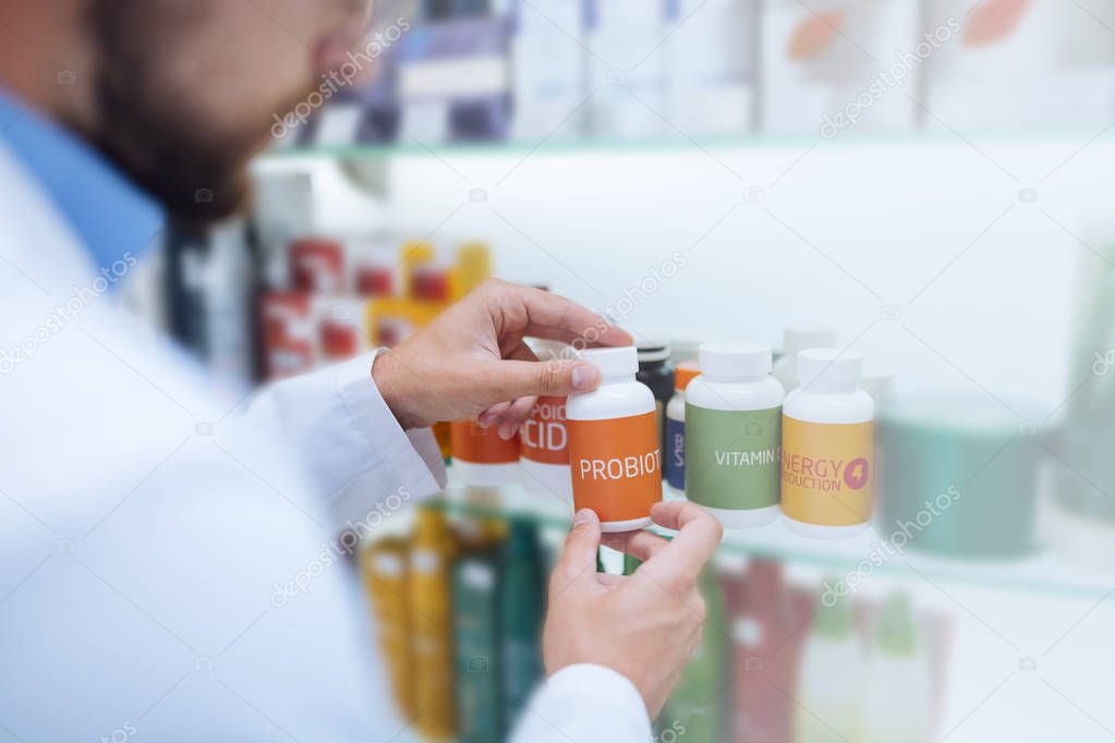 Attentive male person taking package with pills