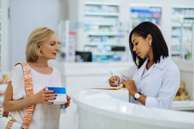 Genç uluslararası eczacı istişare sırasında notlar yapma