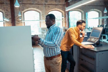 Koyu tenli yayıncı baskı ofisinde çalışmakla meşgul hissediyor