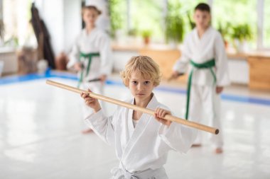 Sevimli sarışın okul çocuğu jo aikido hareketleri pratik tutarak