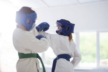 Beyaz kimono ve koruyucu kasklı erkek ve kız kavga ediyor