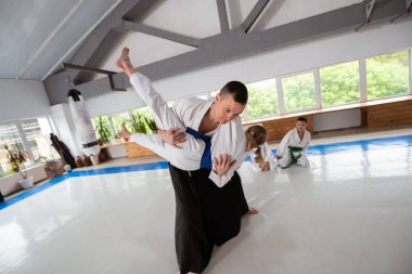 Aikido öğretmen beyaz kimono giyen kız ile atmak yapıyor