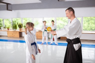 Gülümseyen aikido eğitmen küçük kız ödülü sunan