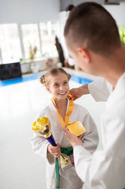 Successful teen girl practicing aikido receiving prizes clipart