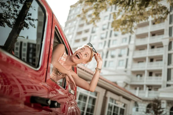 Glad kvinna lutar sig ut ur bilfönstret. — Stockfoto