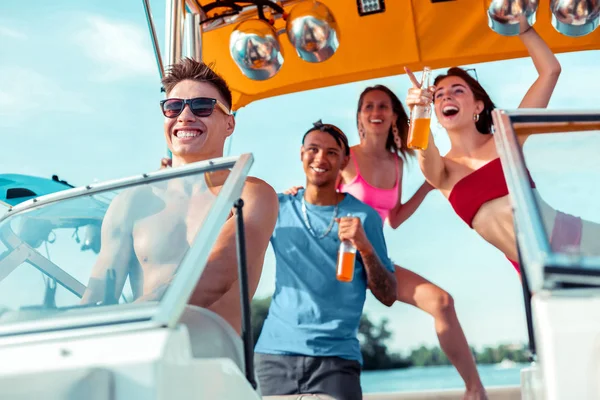 Bonito jovem dirigindo uma lancha com amigos — Fotografia de Stock