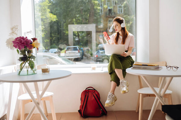 Concentrated longhaired girl reading message on telephone