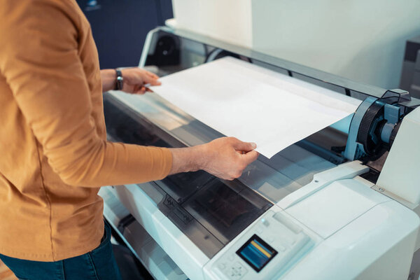 Close up of man wearing orange sweater printing posters