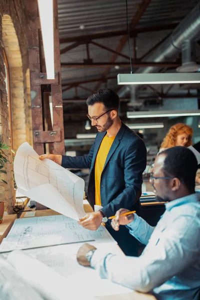 Diseñador de interiores sosteniendo bocetos de pie cerca de colega — Foto de Stock