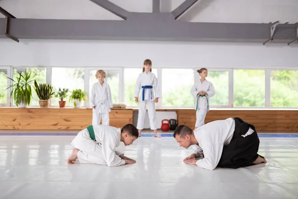 Menino e aikido treinador cumprimentando uns aos outros antes de praticar — Fotografia de Stock