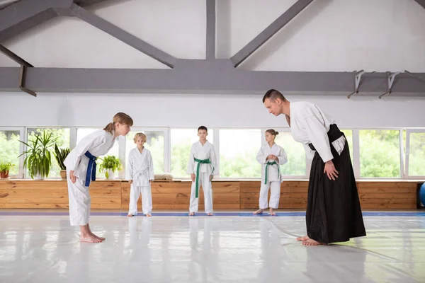 Menina dando um arco para treinador antes de praticar aikido — Fotografia de Stock