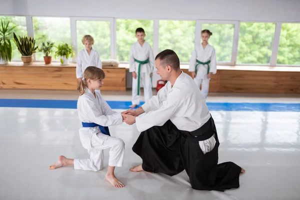 Aikido 를 연습하기 전에 어린 소녀를 인사하는 검은 머리 트레이너 — 스톡 사진