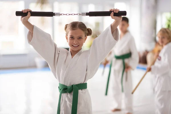 Apelando loira de cabelos menina sorrindo enquanto segurando nunchucks — Fotografia de Stock