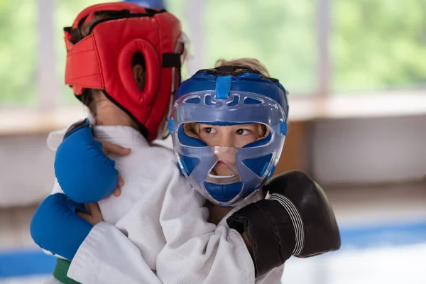 Menino de olhos escuros usando capacete protetor lutando com amigo — Fotografia de Stock