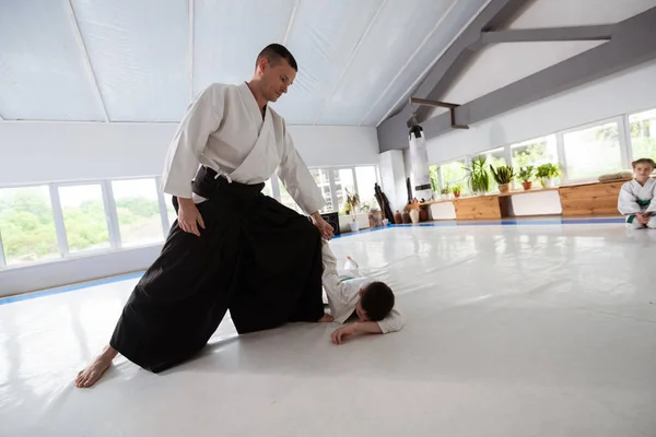Boy lying on floor after having aikido fight with his trainer
