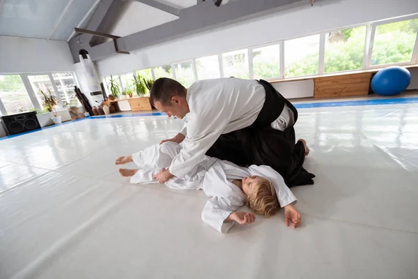 Dark-haired aikido trainer teaching boy to protect himself