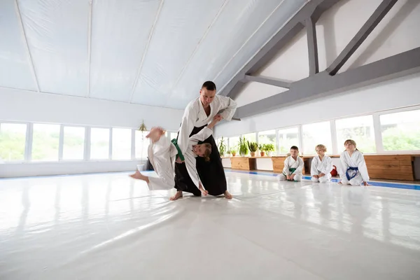 Aikido entrenador lanzando chica en kimono blanco mientras le enseña —  Fotos de Stock
