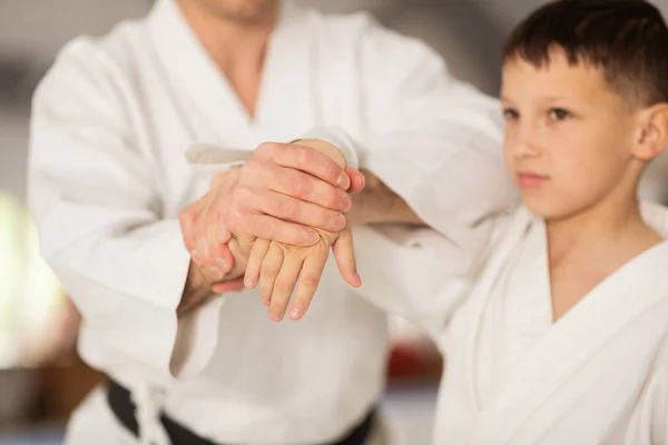 Dark-eyed boy feeling excited learning aikido with trainer