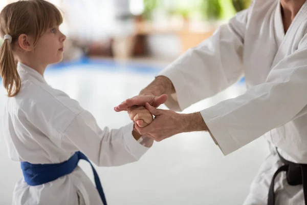 Trainer with black belt showing some aikido movements for girl — Stock Photo, Image