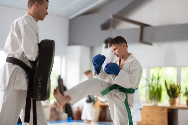 Dunkelhaariger Junge mit Handschuhen, der seine Schläge übt — Stockfoto