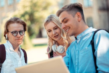 Üç öğrenci dışarıdaki projeye bakıyor.