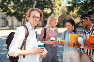 Gülümseyen çocuk grup arkadaşlarıyla kahve içiyor.