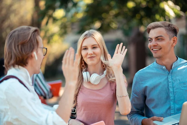 Groupmates giving each other goodbye high-five outside.