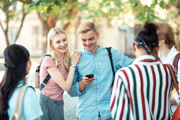 Studentenpaar kommuniziert mit seinen Klassenkameraden draußen. — Stockfoto