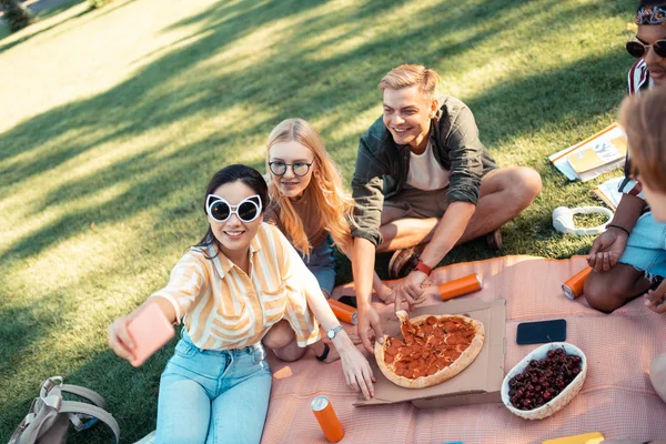 Amigos alegres tomando selfies y comiendo pizza . — Foto de Stock