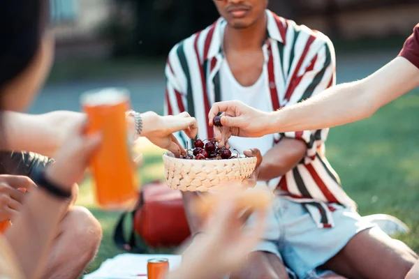 Barátok étkezési cseresznye során nyári piknik. — Stock Fotó