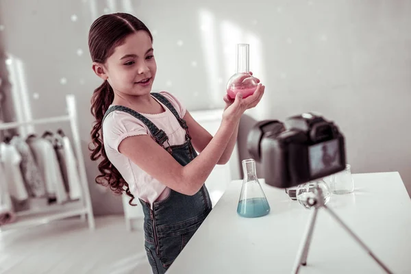 Joyful intelligent girl holding a small flask