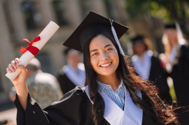 Kampüste diplomasını gösteren gururlu mezun kız.