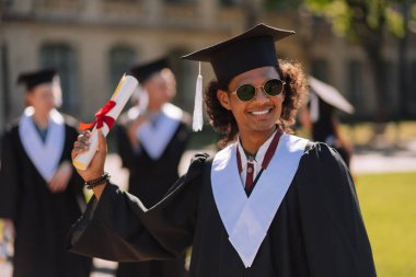 Onun diploması ile neşeli graduant yükselterek el.