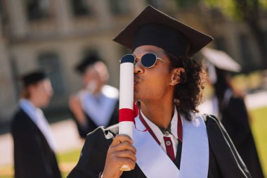 Mutlu graduant onun yeni alınan diploma öpüşme.