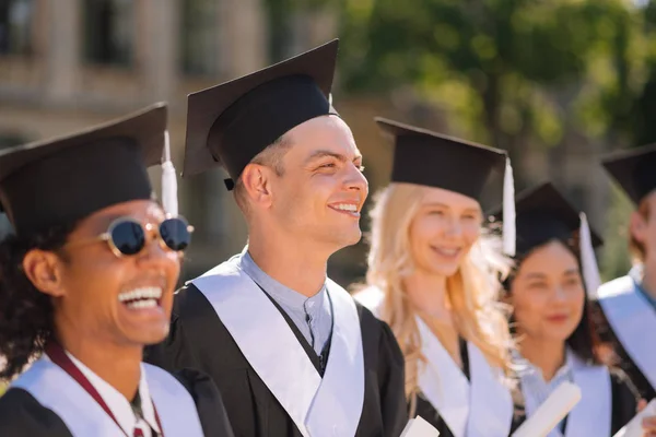 Garçon souriant debout parmi ses amis lors de la cérémonie de remise des diplômes . — Photo