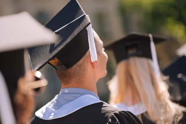 Young graduates wearing masters capes receiving diplomas.