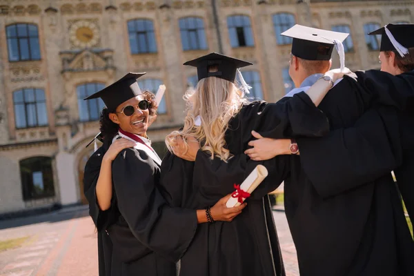 Joyeux garçon étreignant ses camarades de groupe dans la cour de l'université . — Photo